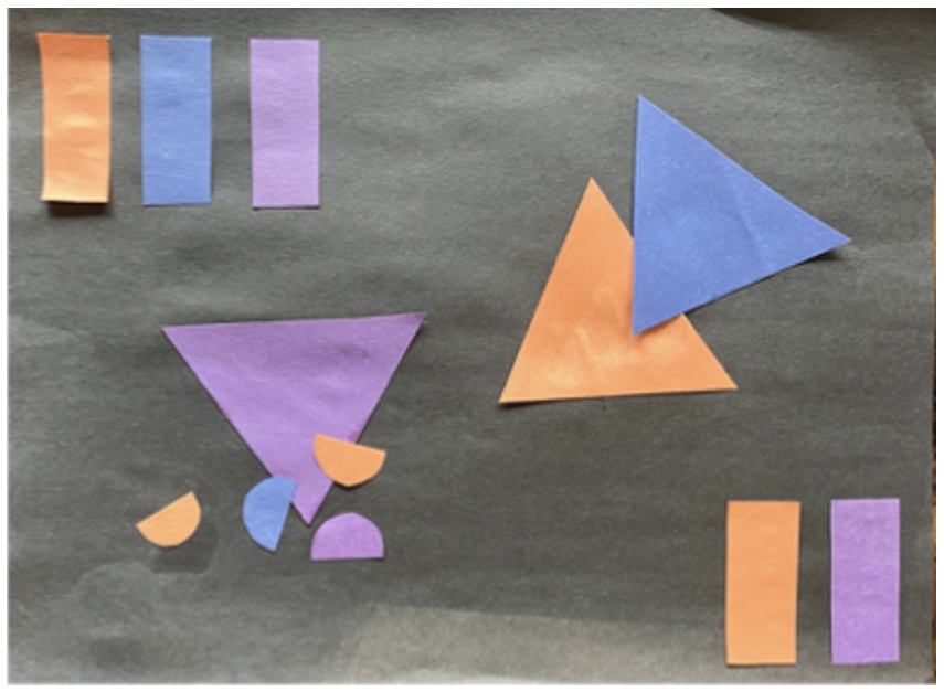 Colored paper shapes on a black background form a Kandinsky-inspired place value collage: rectangles and vibrant triangles and semicircles in blue and orange create an abstract, playful arrangement across the canvas.